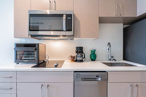 A kitchen with a black microwave on top of a white counter.