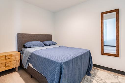 A bedroom with a bed, nightstand, and a mirror.