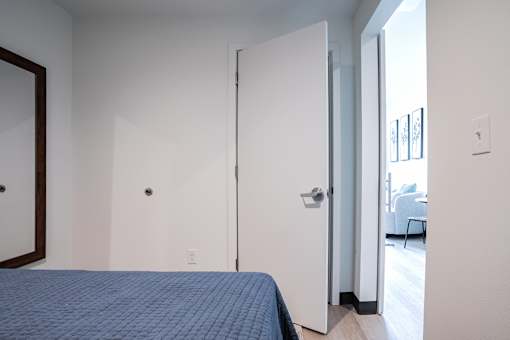 A bedroom with a bed and a mirror on the wall.