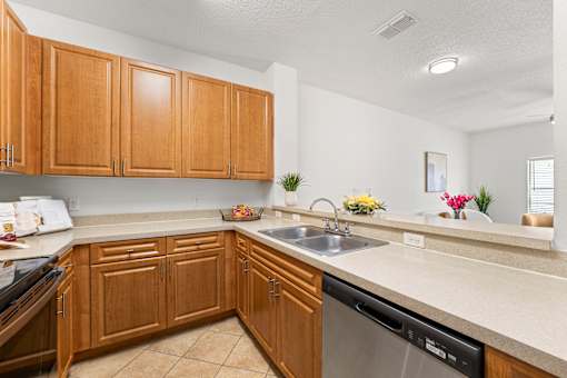 Pet-Friendly Townhomes in Kissimmee, FL – Estates at Lake Cecile -A kitchen with wooden cabinets and a stainless steel dishwasher.