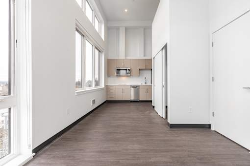 A long, empty room with a kitchen area in the background.