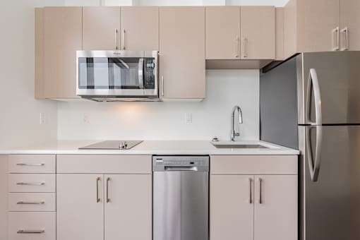 A modern kitchen with a stainless steel refrigerator, microwave, and dishwasher.
