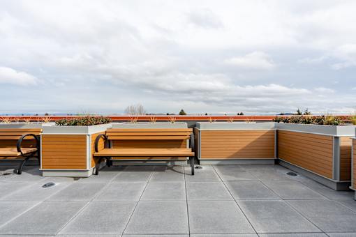 A wooden bench sits on a patio with a view of the horizon.