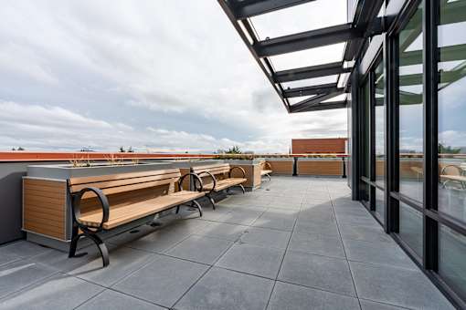 A rooftop patio with benches and a glass wall overlooking the city.