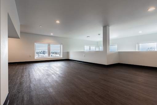 A large empty room with wooden floors and white walls.