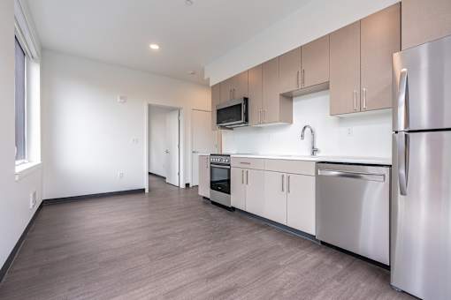 A modern kitchen with stainless steel appliances and wooden flooring.