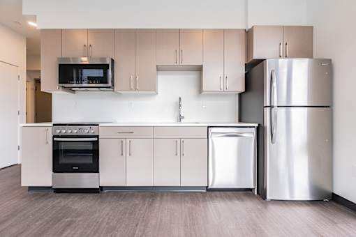 A modern kitchen with stainless steel appliances and wooden flooring.