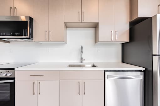 A kitchen with a stainless steel dishwasher and white countertops.