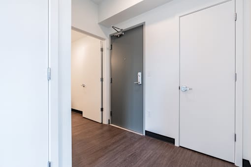A white door is open to a room with a grey door.