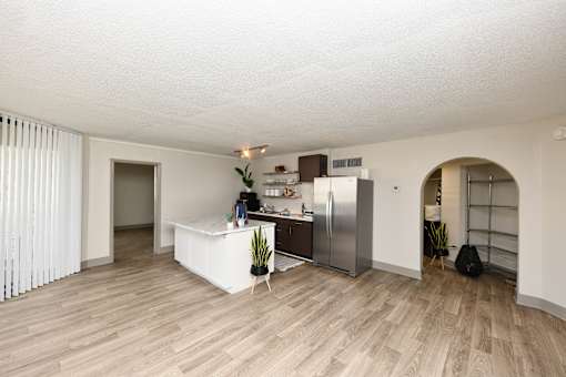 A kitchen area with a refrigerator, a counter, and a potted plant.