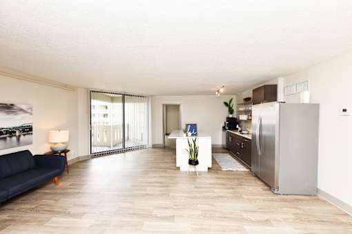 A modern kitchen with a blue sofa and wooden flooring.