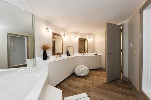 A white bathroom with a large tub and a vanity with a mirror.
