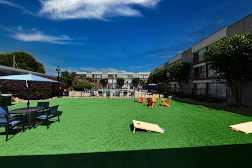 A playground with a green surface and various pieces of play equipment.