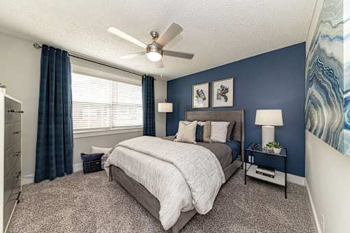 Hendersonville, TN Apartments – Reserve at Drakes Creek -A bedroom with a bed, nightstand, and a ceiling fan.
