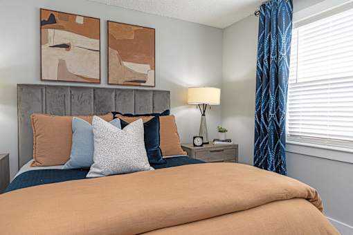 Apartments In Hendersonville, TN 37075 for Rent – Reserve at Drakes Creek –A bedroom with a bed, nightstand, and two abstract paintings on the wall.