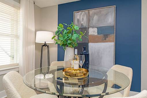 Apartments In Hendersonville, TN 37075 for Rent – Reserve at Drakes Creek –A glass dining table with a plant and a bottle of wine on it.