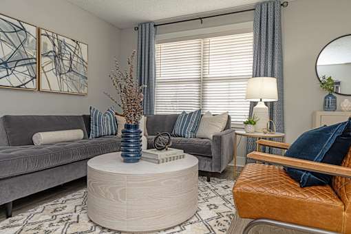 Apartments In Hendersonville, TN 37075 for Rent – Reserve at Drakes Creek –A living room with a grey couch, a round coffee table, and a painting on the wall.