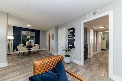 Hendersonville, TN Apartments – Reserve at Drakes Creek -A living room with a brown leather couch and a dining table with chairs.