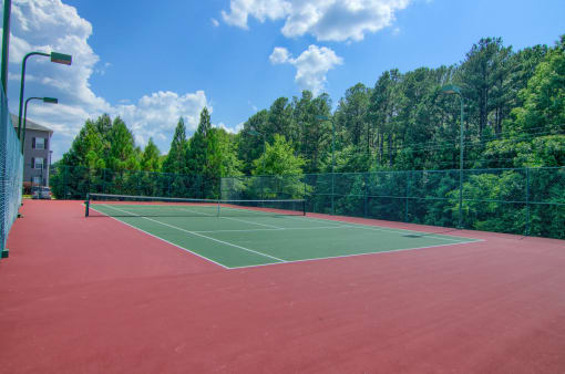 Outdoor tennis court at Lancaster Place in Calera, Alabama, with clean playing surface and surrounding fencing.