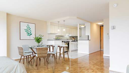 A dining room with a table set for six with a plant on the table.