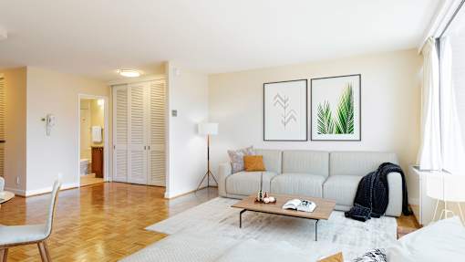 A living room with a white couch and a painting on the wall.