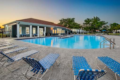 A poolside area with blue lounge chairs and a building in the background.