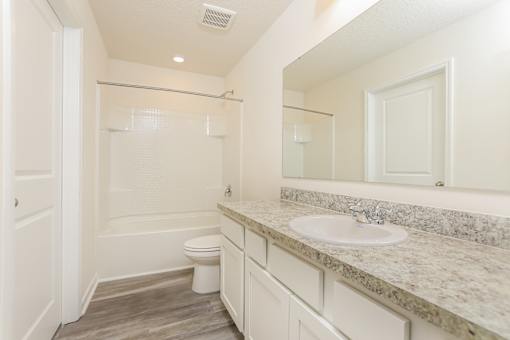 A white bathroom with a toilet, sink, and mirror.