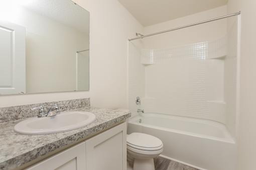 A white bathroom with a sink, toilet and bathtub.