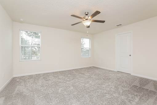 A room with a ceiling fan and carpeted floor.