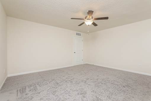 A room with a ceiling fan and carpeted floor.