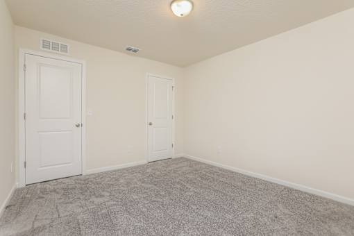 A room with two doors and a carpeted floor.