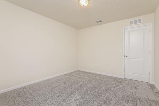 A room with a carpeted floor and a white door.
