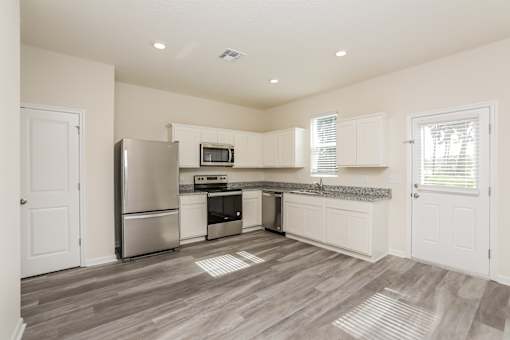 A kitchen with a refrigerator, microwave, oven, and sink.