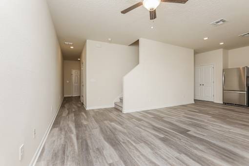 A room with a ceiling fan and a refrigerator.