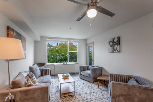Apartments in Fremont, WA for Rent - Epicenter - Furnished Living Room with Ceiling Fan, Large Window, and Patio/Balcony Access