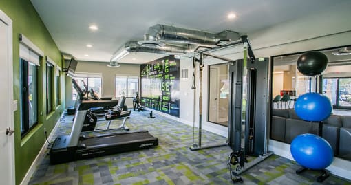 Apartments Near Sky Zone Trampoline Park - Haven at Lone Mountain - A Fitness Center With Treadmills, Strength Training Equipment, Exercise Balls, TV, And Modern Lighting.