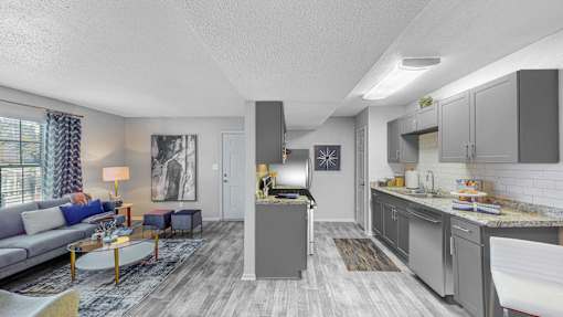 Open-concept living room and modern kitchen at Broad on the Green in Augusta, GA, featuring spacious design and contemporary finishes in a pet-friendly apartment community.