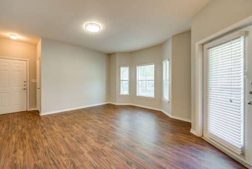 Grand Prairie Apartments - Forum at Grand Prairie - Open Concept Living Room with Large Windows and Hardwood Flooring