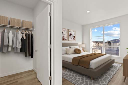 A bedroom with a large bed and a wardrobe with clothes hanging.