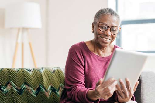 Senior woman using tablet in stylish apartment at Sage 5430 Norcross 55+ community