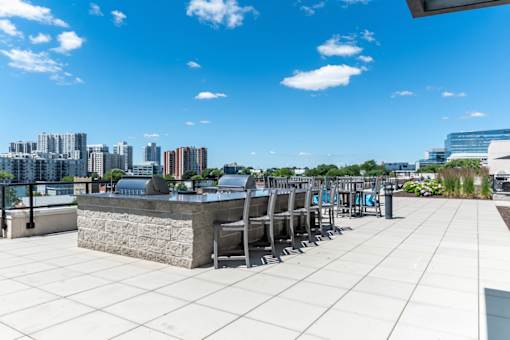 A rooftop patio with a stone barrier and several chairs.