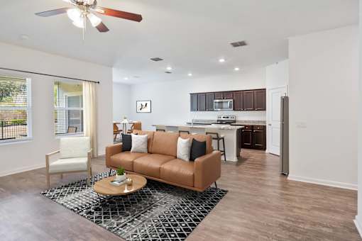 A living room with a brown couch and a ceiling fan.