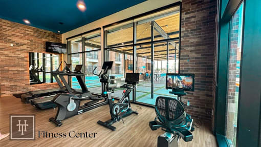 Heritage Towers Apartments a gym with cardio equipment and a pool in the background lewisville tx apartments apartments near lewisville tx lewisville apartments