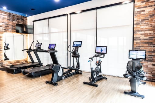 a workout room with treadmills and televisions in a fitness center