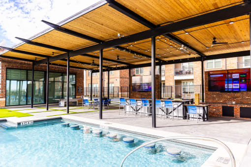 the pool is under a covered patio with tables and chairs