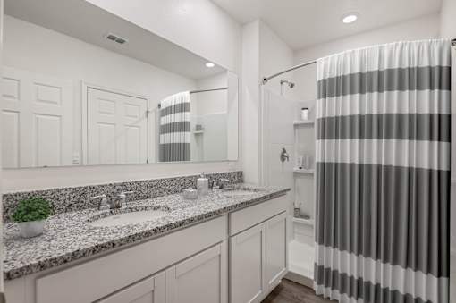 A bathroom with a striped shower curtain and a marble countertop.