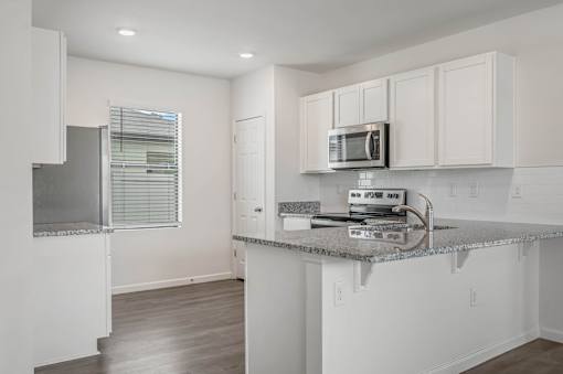 A kitchen with white cabinets and a granite countertop.