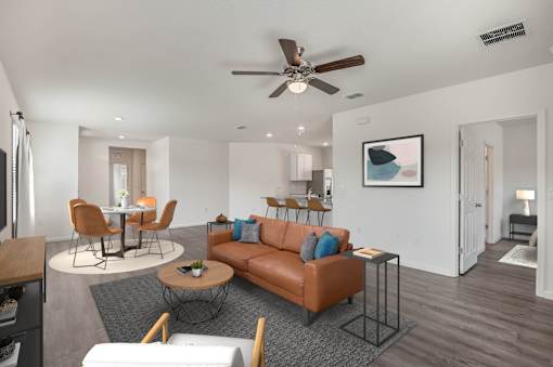 A living room with a brown couch and a ceiling fan.