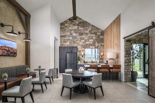 A modern dining room with a stone fireplace and grey chairs.