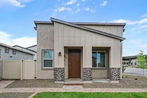 A modern house with a brown door and a grey facade.